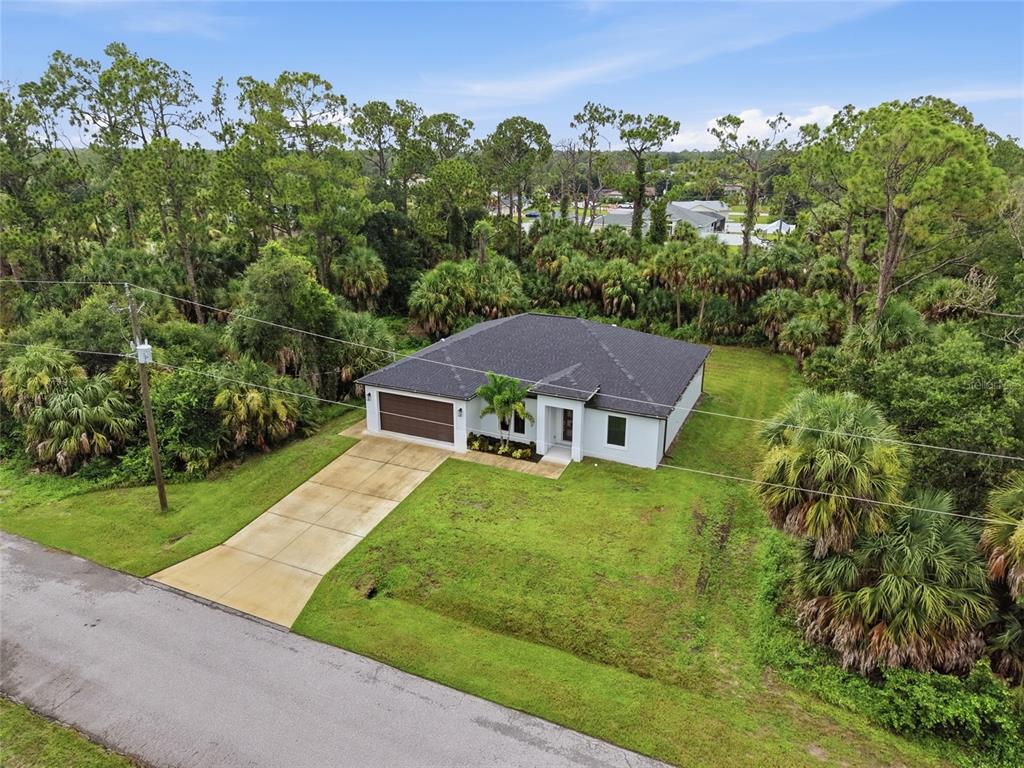 An aerial view shows a single-story house with a dark roof and a concrete driveway — 14390 MADDOCK AVENUE, PORT CHARLOTTE, FL