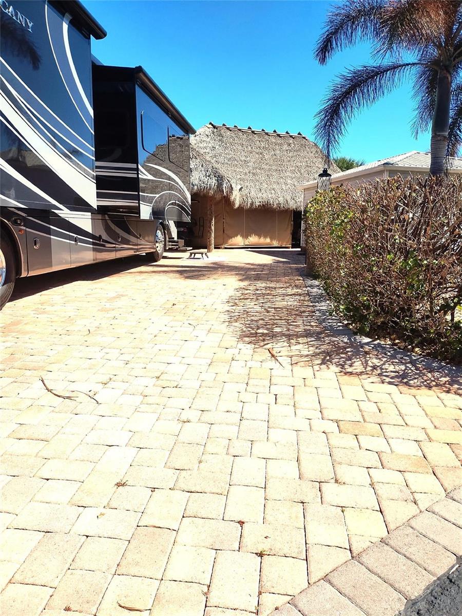 A paved driveway leads to a thatched-roof structure next to a parked recreational vehicle — Lot 209 3720 SW 7th Manor, Okeechobee FL 34974, OKEECHOBEE, FL