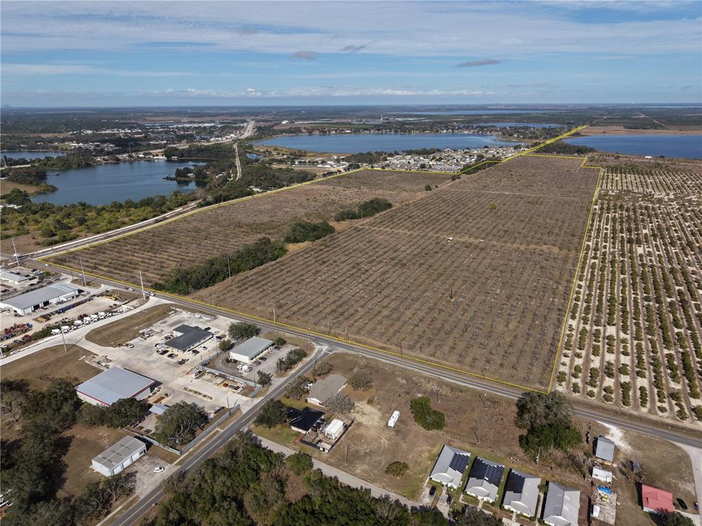An aerial view shows a large, rectangular agricultural plot outlined in yellow near a lake — 214 E SHOCKLEY ROAD, AVON PARK, FL