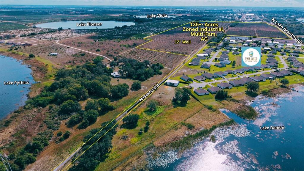 This aerial view shows a large plot of land bordered by lakes and a road — 214 E SHOCKLEY ROAD, AVON PARK, FL
