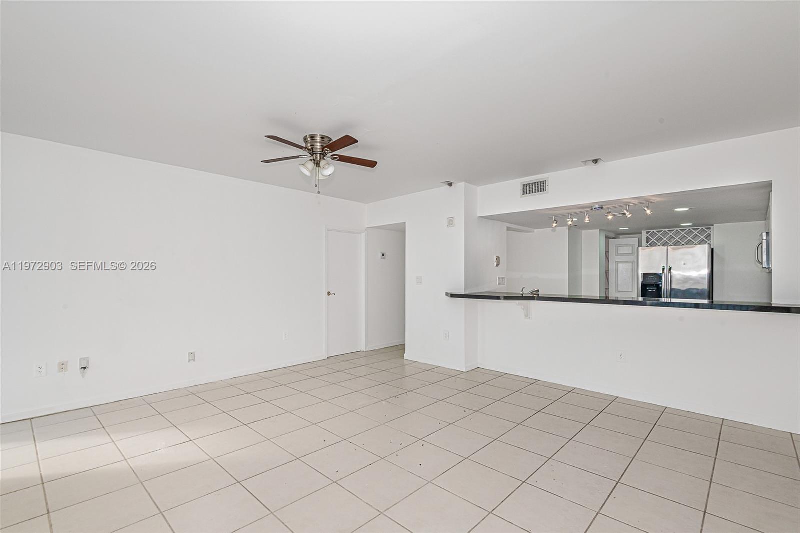 An empty room with white walls, tile flooring, a ceiling fan, and a kitchen pass-through — 555 NE 15th St # 603, Miami FL 33132, MIAMI, FL