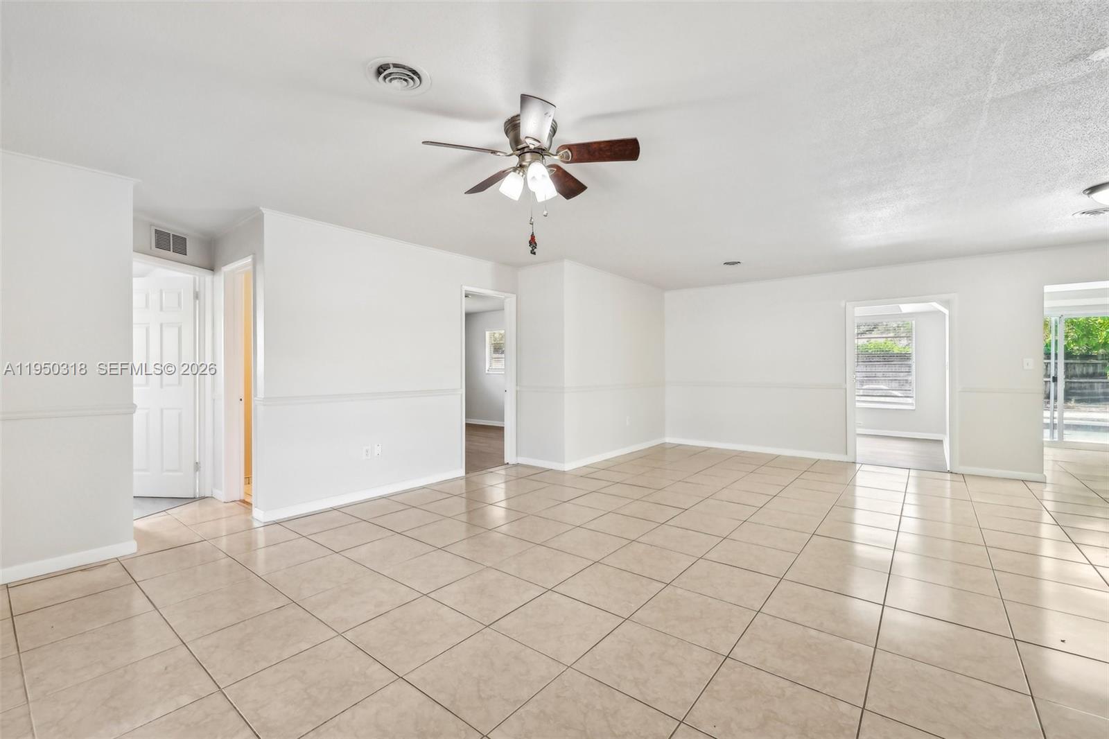 A spacious, tiled living area features white walls, a ceiling fan, and multiple doorways — 334 NW 12th Ave, Boca Raton FL 33486, BOCA RATON, FL
