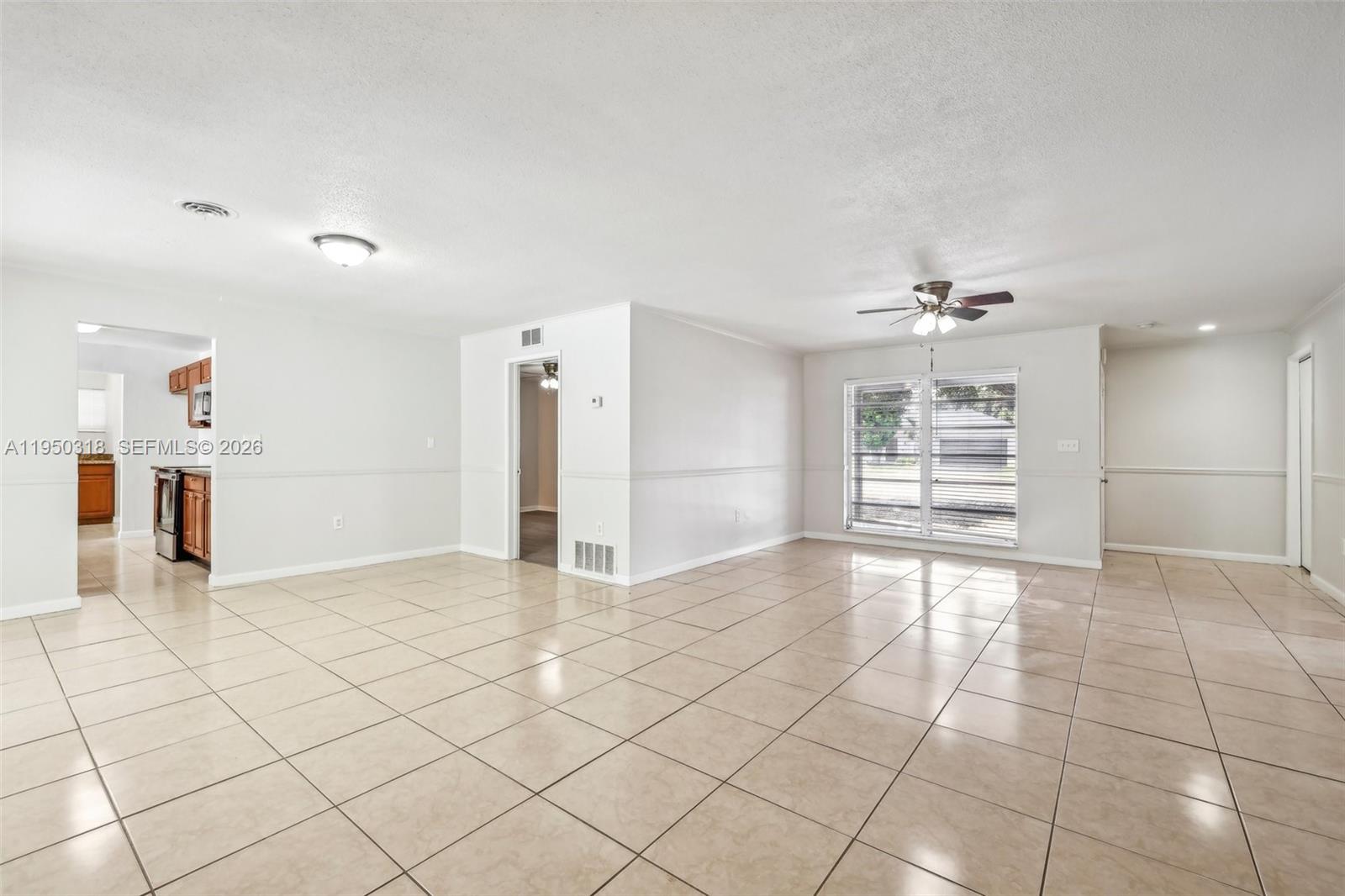 A spacious, tiled living area features a ceiling fan, recessed lighting, and an adjacent kitchen — 334 NW 12th Ave, Boca Raton FL 33486, BOCA RATON, FL