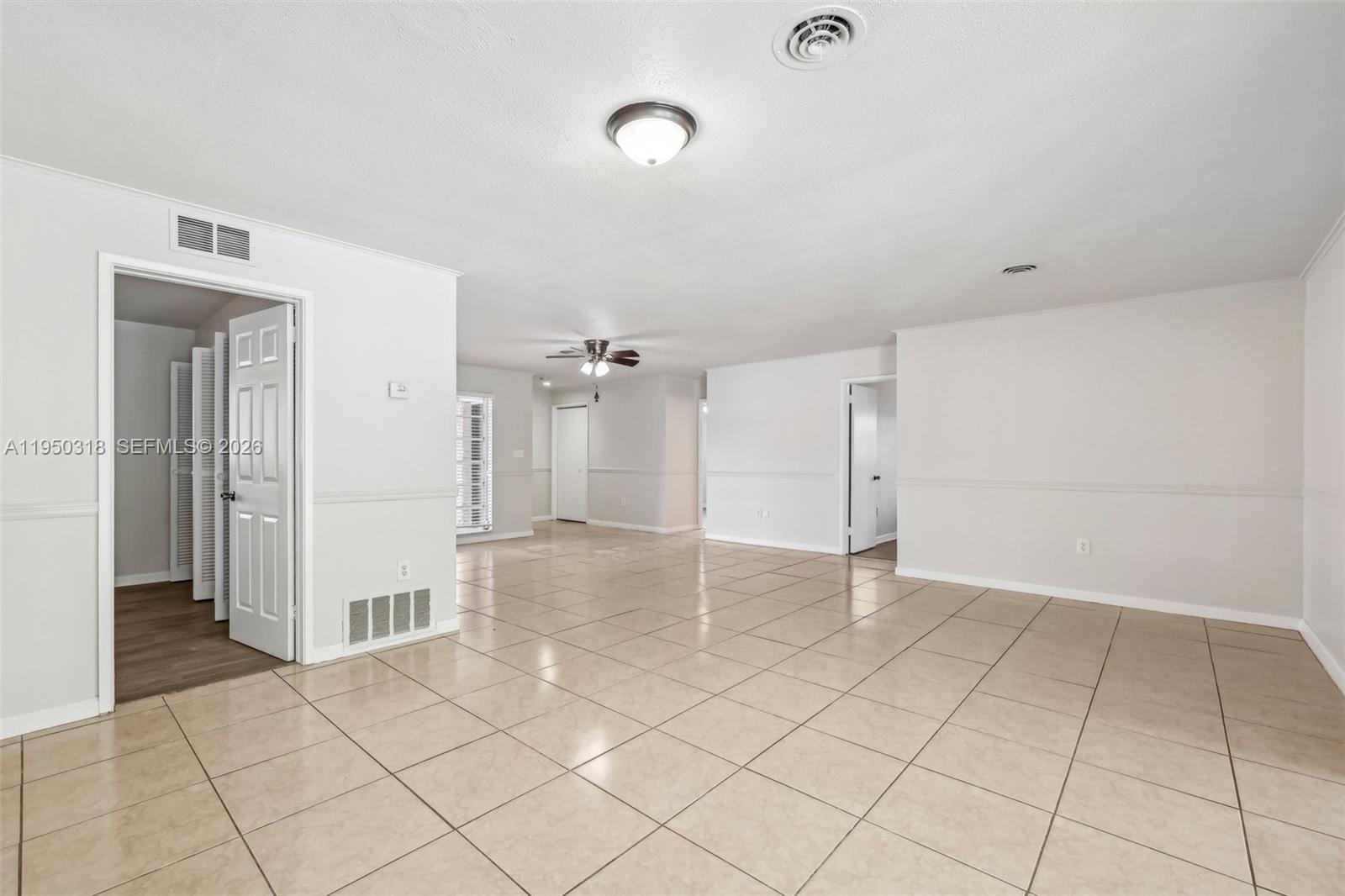 An interior view of a spacious living area featuring light-colored tile flooring and white walls — 334 NW 12th Ave, Boca Raton FL 33486, BOCA RATON, FL