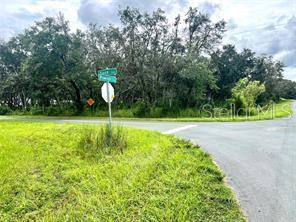 A street sign stands at a rural intersection surrounded by trees and grassy fields — SIOUX TRAIL, KISSIMMEE, FL