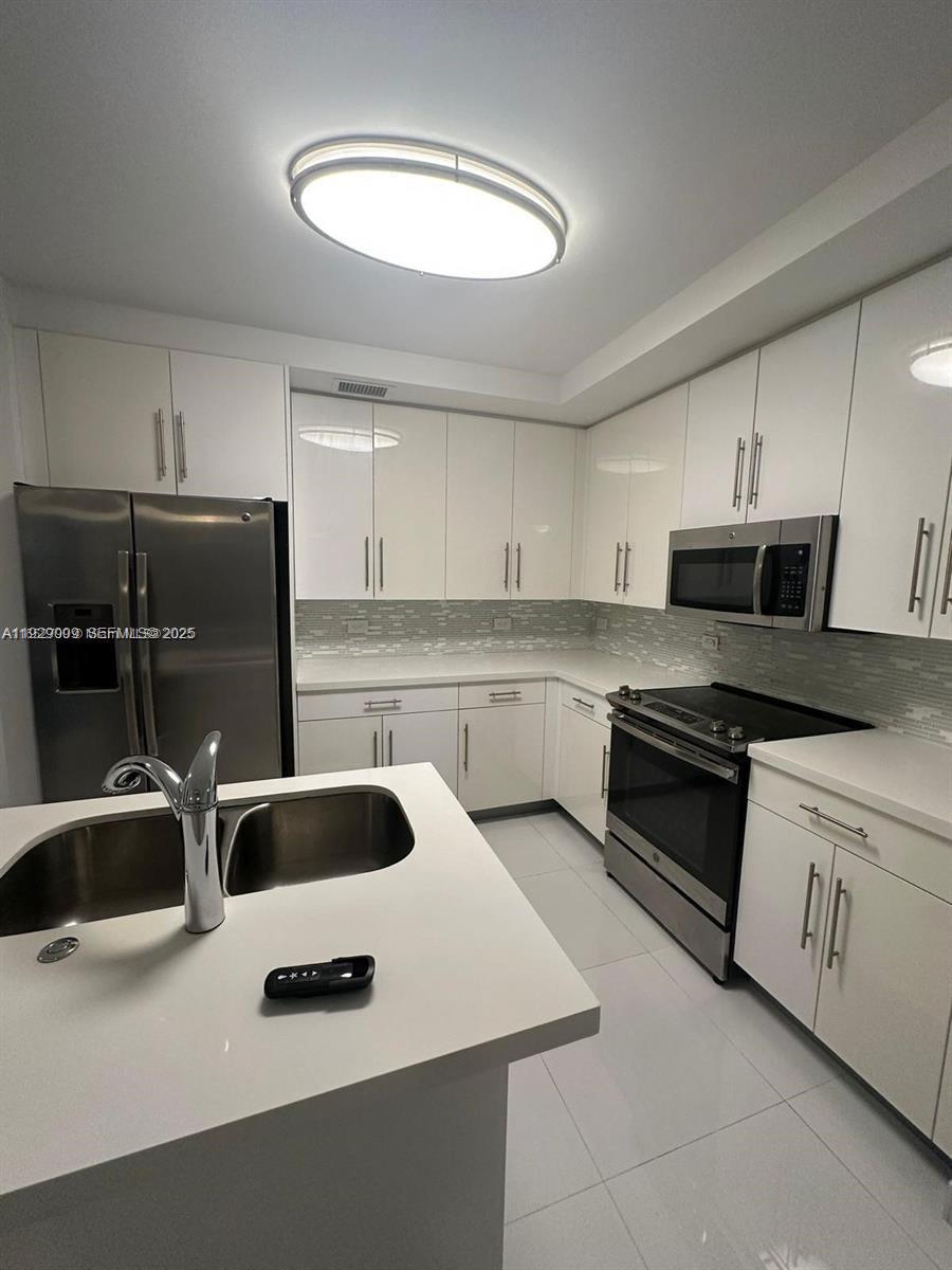 A modern kitchen features white cabinets, stainless steel appliances, and a white quartz island — 2651 NE 212th Ter # 400, Miami FL 33180, MIAMI, FL