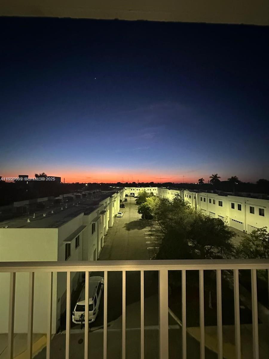 An elevated view shows a parking lot between two rows of white townhouses at sunset — 2651 NE 212th Ter # 400, Miami FL 33180, MIAMI, FL