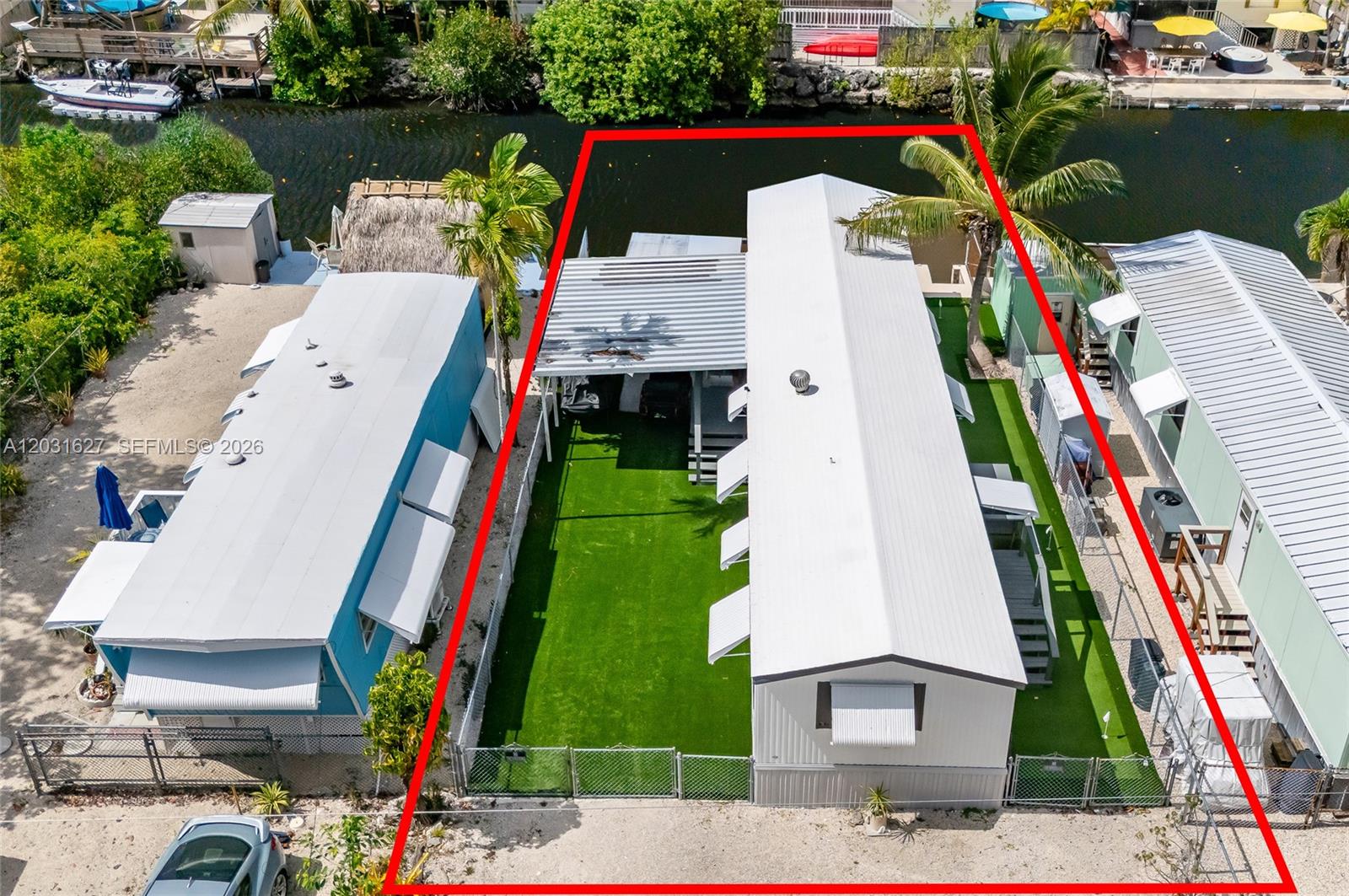 An aerial view shows a mobile home with a green lawn and a canal — 456 Bowie Ln, Key Largo FL 33037, KEY LARGO, FL