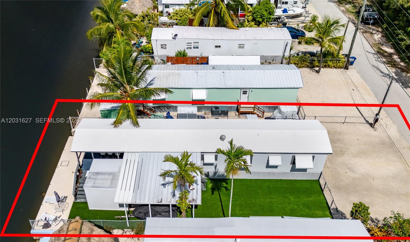 An aerial view shows a mobile home with a green lawn situated along a canal — 456 Bowie Ln, Key Largo FL 33037, KEY LARGO, FL