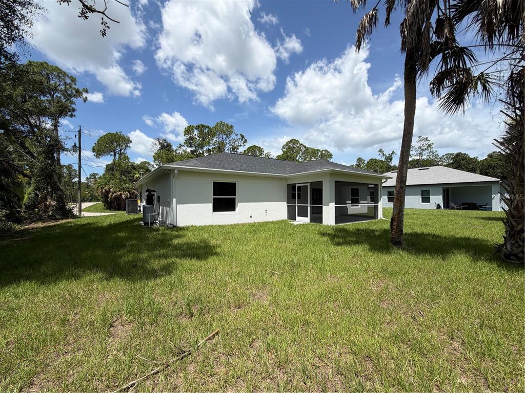 The exterior of a single-story house with a screened-in porch and a grassy backyard — 2584 CHESLEY ROAD, NORTH PORT, FL