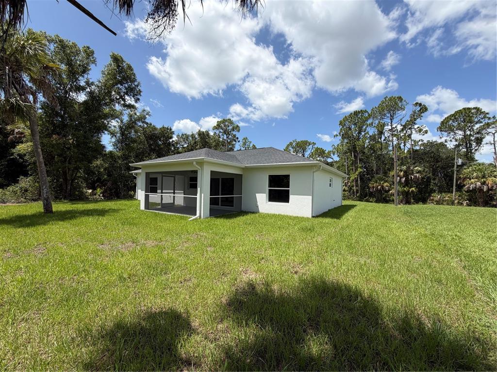 A white single-story house with a screened-in back porch sits on a large grassy lot — 2584 CHESLEY ROAD, NORTH PORT, FL