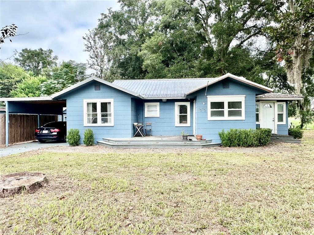 A blue single-story house with a metal roof, a carport, and a front deck — 1515 NE 55TH STREET, OCALA, FL