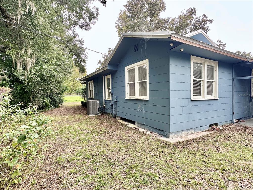 The exterior of a blue house features white-trimmed windows and an air conditioning unit — 1515 NE 55TH STREET, OCALA, FL