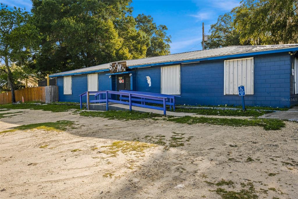 A blue, single-story commercial building features a wooden wheelchair ramp and a sandy lot — 3025 S US HIGHWAY 41, DUNNELLON, FL