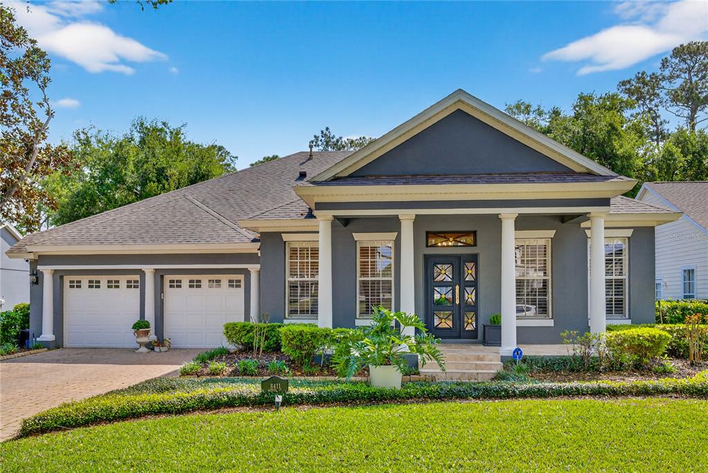 A single-story gray house with a front porch, white columns, and a two-car garage — 8411 WOBURN COURT, WINDERMERE, FL