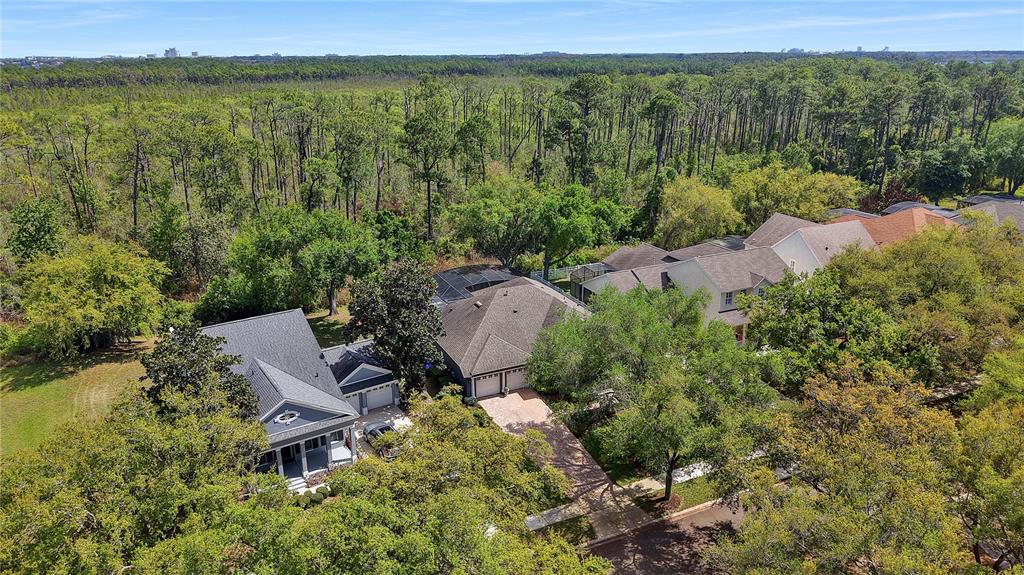 An aerial view shows two houses surrounded by trees with a large forest in the background — 8411 WOBURN COURT, WINDERMERE, FL