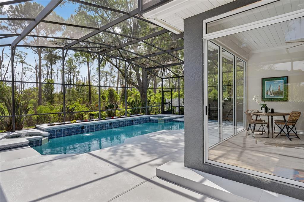 A screened-in patio features a rectangular swimming pool with a spa and tile accents — 8411 WOBURN COURT, WINDERMERE, FL