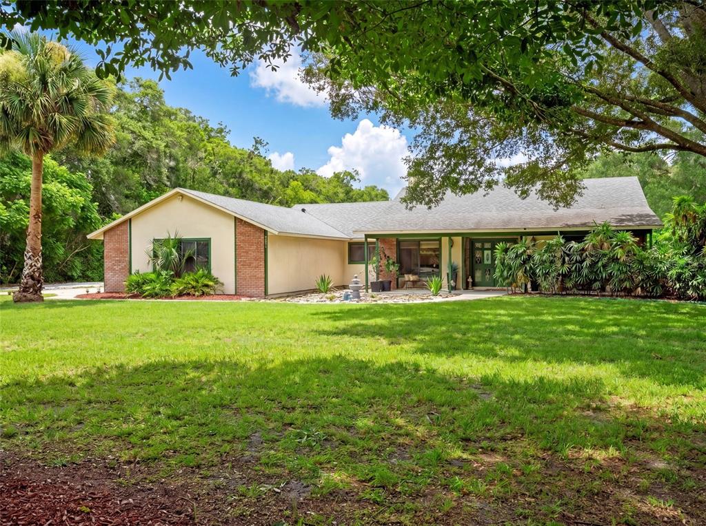 A single-story house with brick accents, a green-trimmed porch, and a large front lawn — 3501 HILL STREAM AVENUE, APOPKA, FL