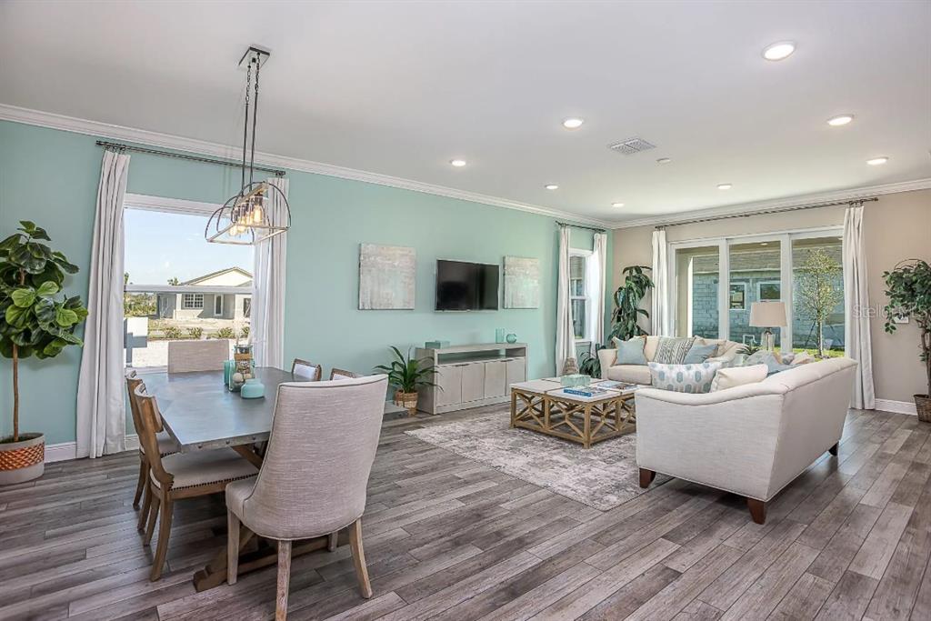 An open-concept living and dining area features light blue walls, wood-look flooring, and sliding doors — 26 DOUGLAS COURT S, HOMOSASSA, FL