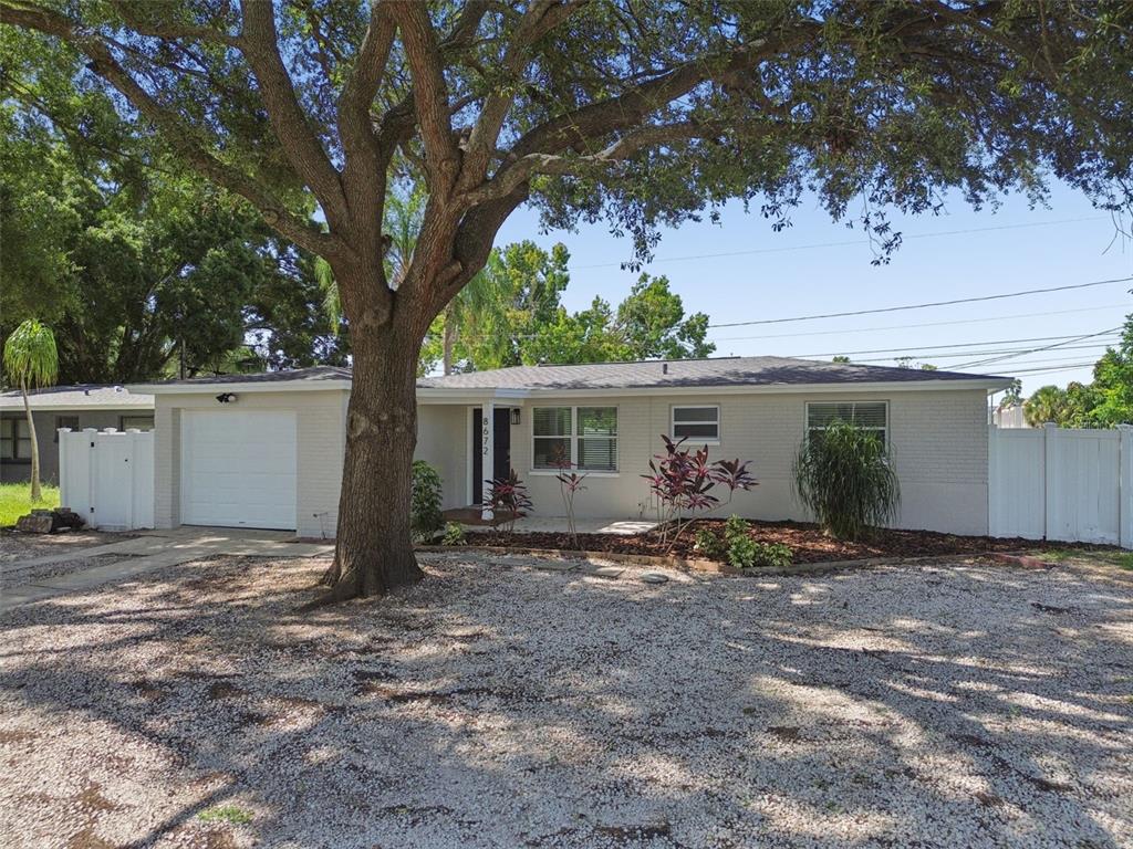 A single-story house with a white brick exterior, a garage, and a large front tree — 8672 78TH PLACE, SEMINOLE, FL