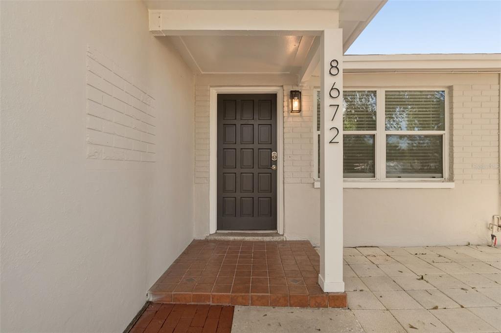 A front entryway features a dark brown door, tiled porch, and white brick exterior walls — 8672 78TH PLACE, SEMINOLE, FL