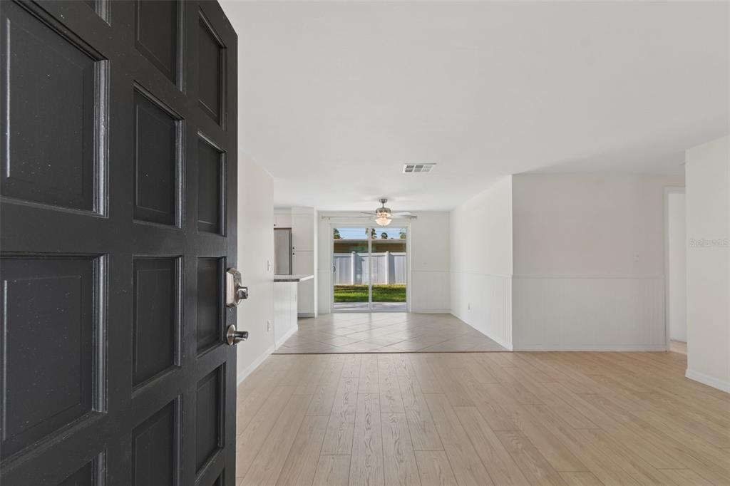A view from an open front door into a living area with light wood flooring — 8672 78TH PLACE, SEMINOLE, FL