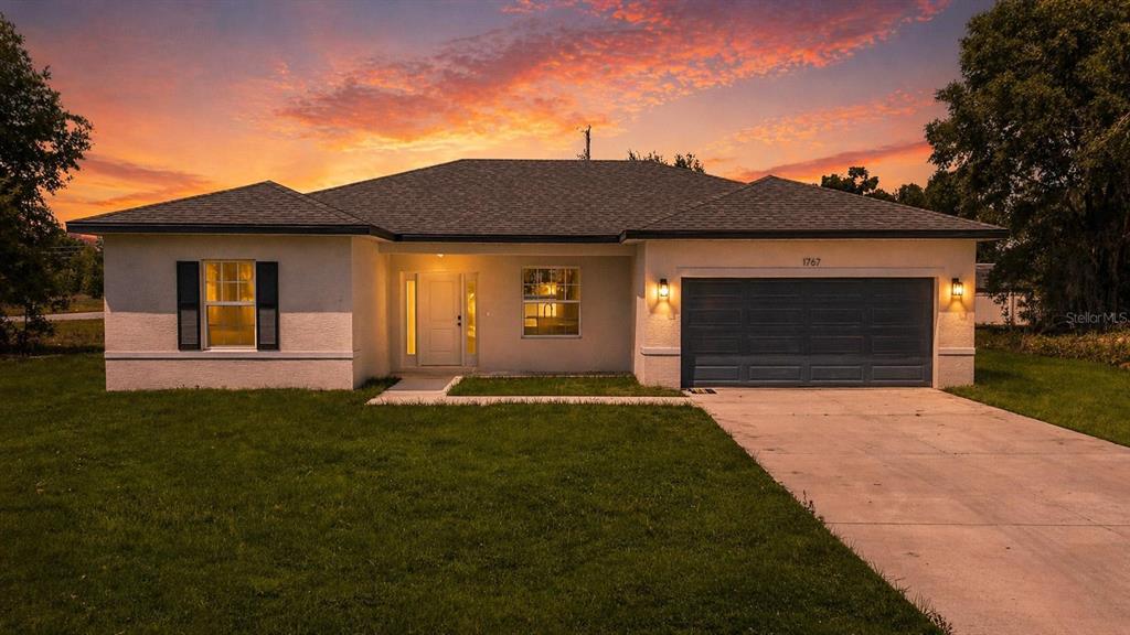 A single-story house with a white stucco exterior, a two-car garage, and a concrete driveway — 1767 SW 166TH STREET, OCALA, FL