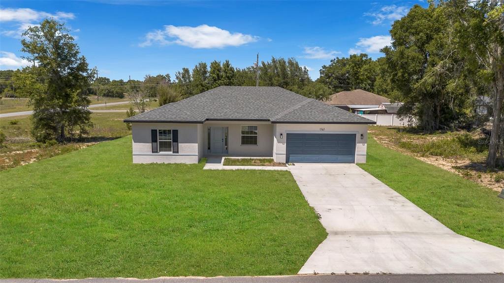 A single-story house with a gray roof, light-colored stucco exterior, and a two-car garage — 1767 SW 166TH STREET, OCALA, FL