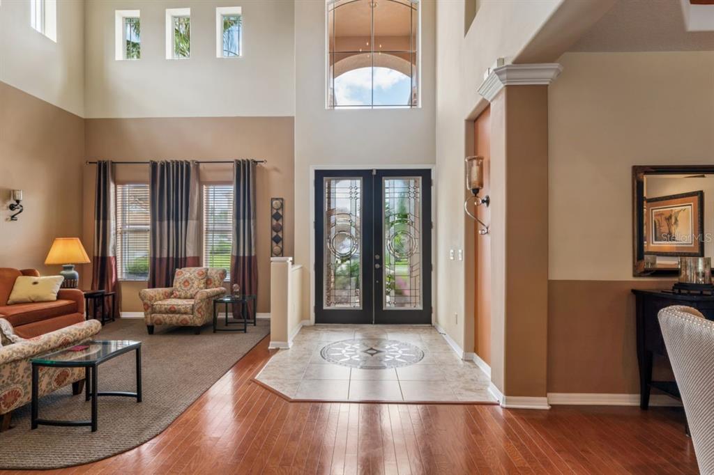 An entryway with tile flooring, hardwood floors, a high ceiling, and double glass front doors — 8719 CREEDMOOR LANE, NEW PORT RICHEY, FL