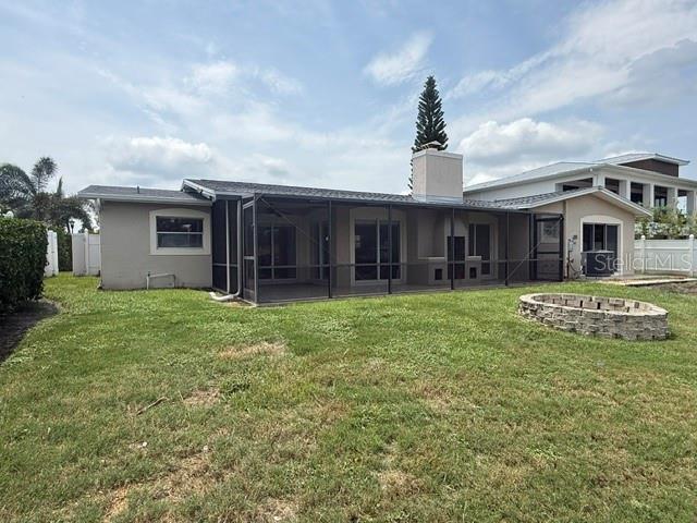 The exterior of a house features a screened-in patio, a chimney, and a stone fire pit — 3945 FONTAINEBLEAU DRIVE, TAMPA, FL