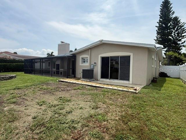 The exterior of a beige house features a screened-in patio and a grassy backyard — 3945 FONTAINEBLEAU DRIVE, TAMPA, FL