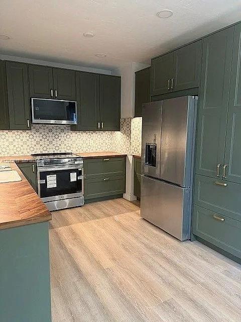 A kitchen features olive green cabinets, stainless steel appliances, and wood-look flooring — 3053 SW 21st St, Miami FL 33145, MIAMI, FL