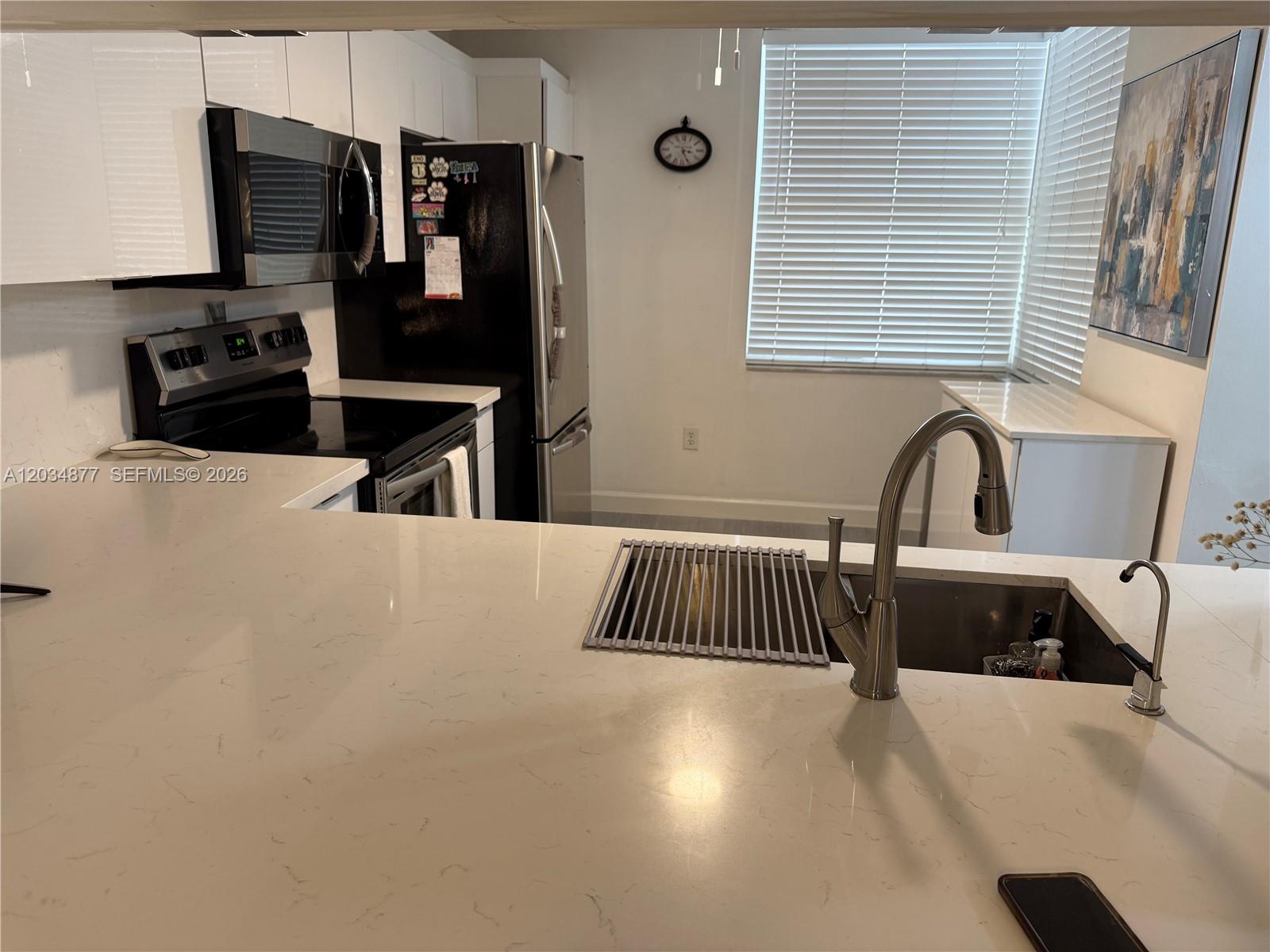 A kitchen features white countertops, stainless steel appliances, and a sink with a pull-down faucet — 10312 NW 24th Pl # 106, Sunrise FL 33322, SUNRISE, FL