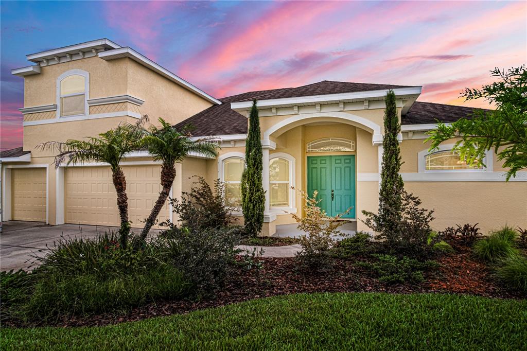A single-story house with a teal front door, arched entryway, and a two-car garage — 2938 SERENO POINTE DRIVE, TITUSVILLE, FL