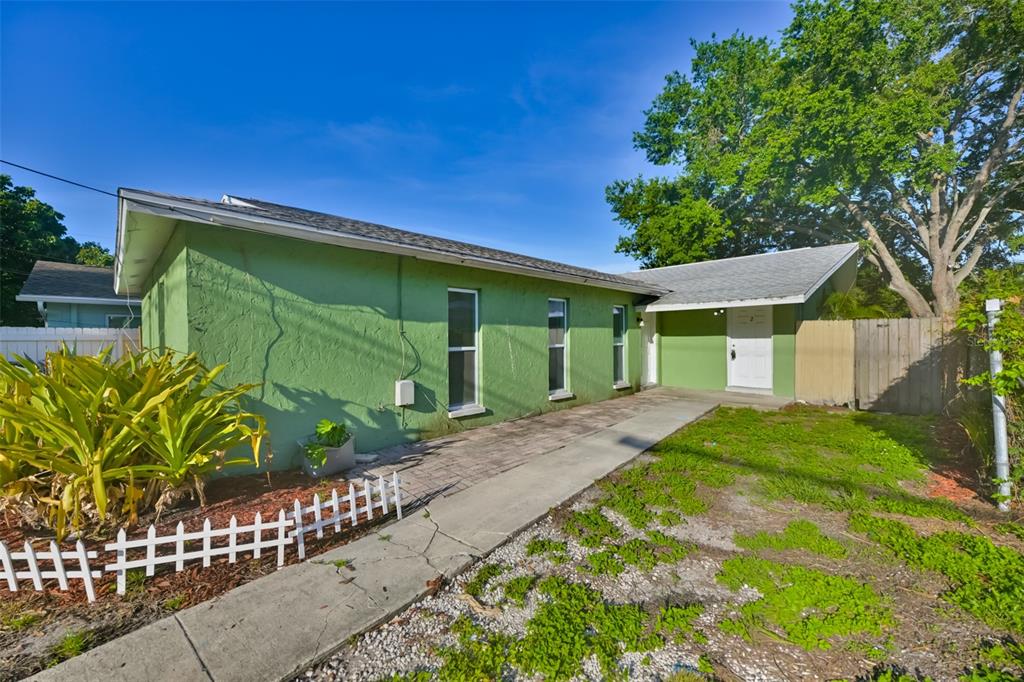 A green, single-story house with a white door, concrete walkway, and a small white fence — 15616 AVALON AVENUE UNIT 1, CLEARWATER, FL