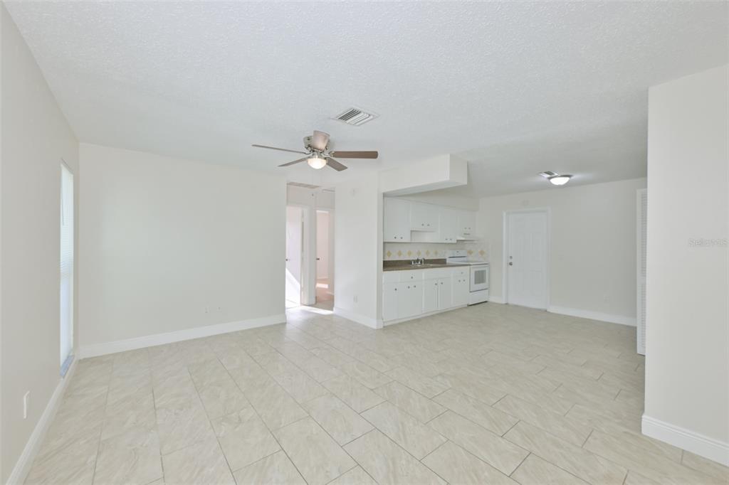 An open-concept living area with light tile flooring, a ceiling fan, and a white kitchen — 15616 AVALON AVENUE UNIT 1, CLEARWATER, FL