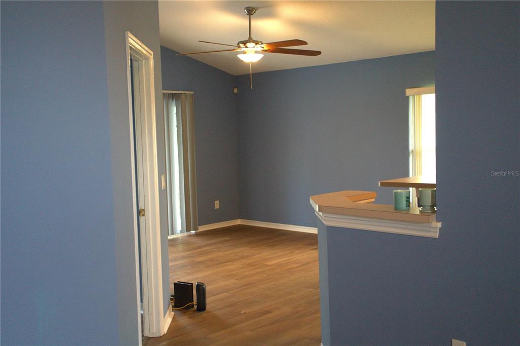 A blue-walled room with wood-look flooring, a ceiling fan, and a kitchen breakfast bar — 209 WESTMORELAND CIRCLE, KISSIMMEE, FL