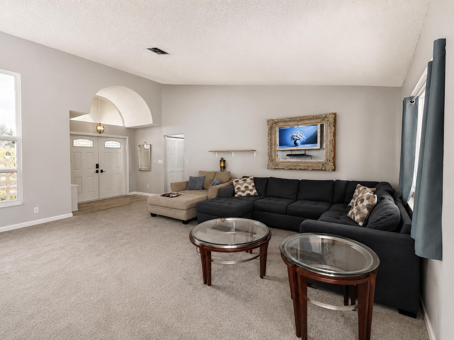 A living room features a large dark sectional sofa, two glass-topped tables, and arched entryway — 2171 Amesbury Circle, Wellington FL 33414, WELLINGTON, FL
