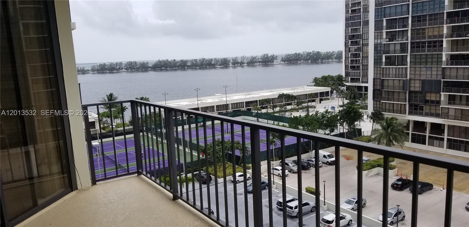 A balcony overlooks a parking lot, tennis courts, and a body of water — 1901 Brickell Ave # B906, Miami FL 33129, MIAMI, FL