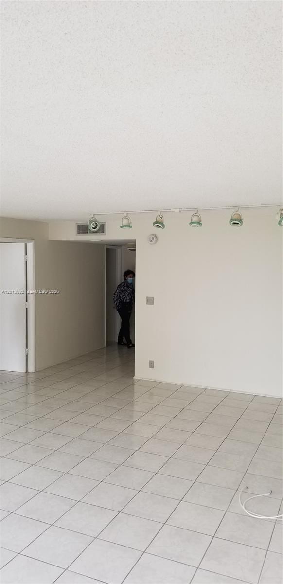 An interior view shows a room with white walls, tiled floors, and track lighting — 1901 Brickell Ave # B906, Miami FL 33129, MIAMI, FL