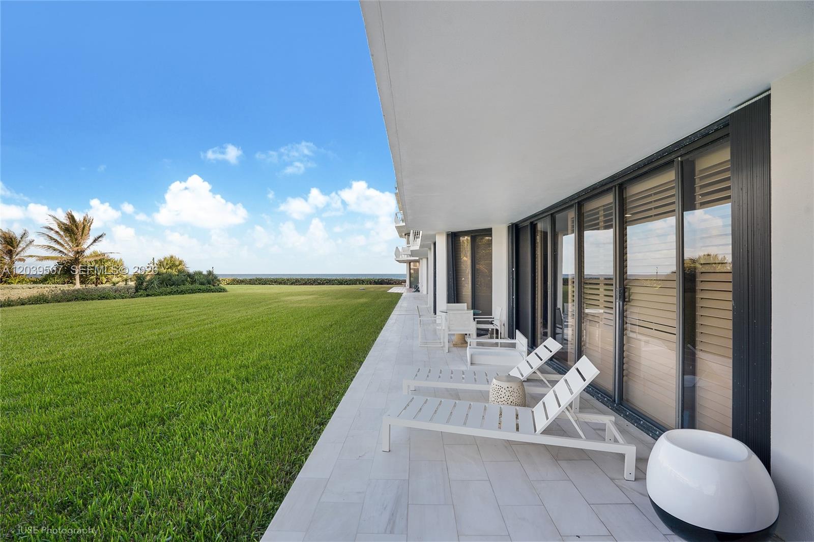 A patio with white lounge chairs overlooks a grassy lawn and the ocean — 2100 S Ocean Boulevard # 103N, Palm Beach FL 33480, PALM BEACH, FL
