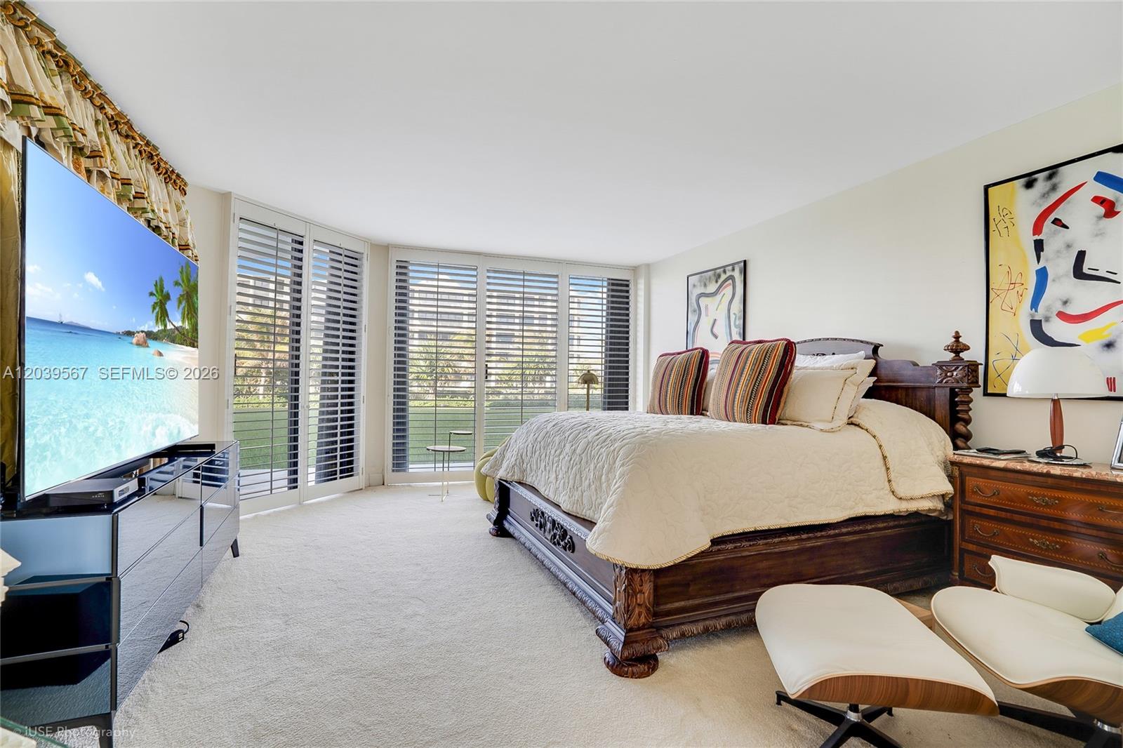 A bedroom features a dark wood bed, a large television, and floor-to-ceiling windows with shutters — 2100 S Ocean Boulevard # 103N, Palm Beach FL 33480, PALM BEACH, FL