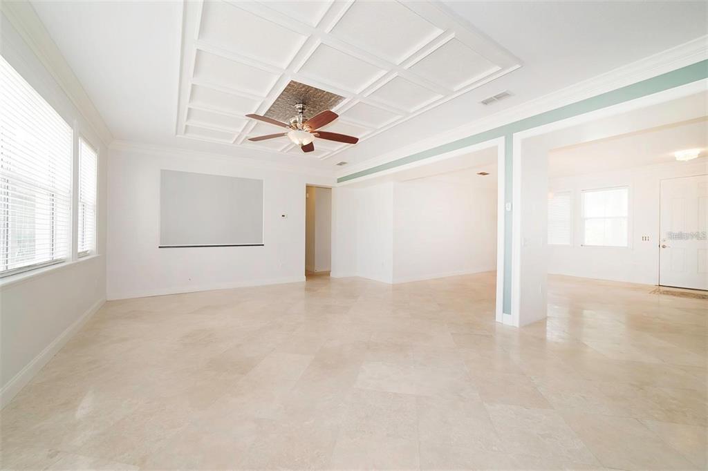 A spacious, bright living room features a coffered ceiling, tile flooring, and a ceiling fan — 10124 MALPAS POINT, ORLANDO, FL