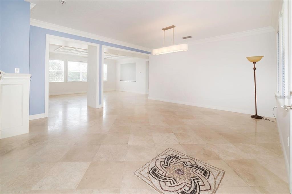 An empty room with light-colored tile flooring, a mosaic inlay, and a modern pendant light — 10124 MALPAS POINT, ORLANDO, FL