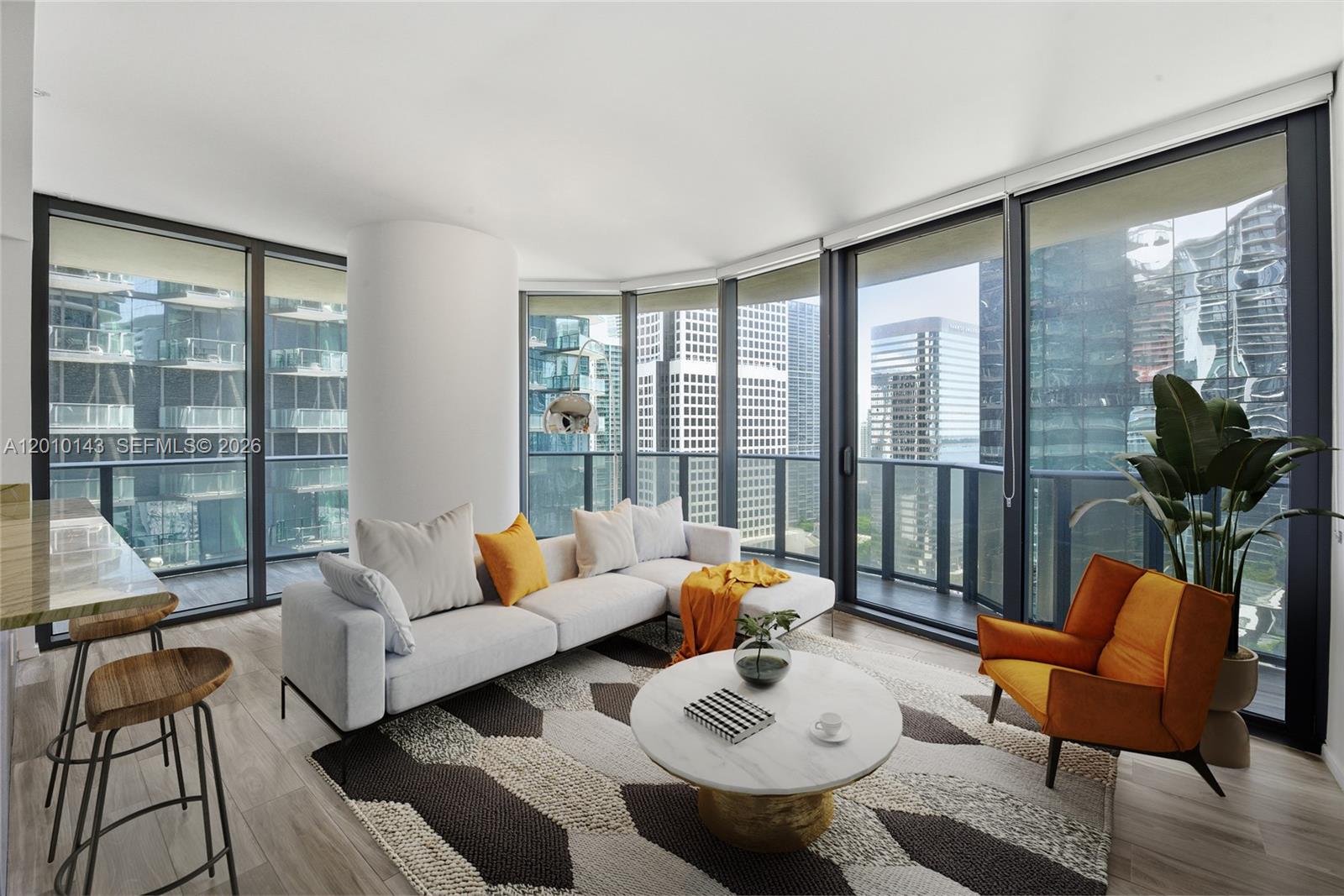 A modern living room features a white sectional sofa, orange accents, and floor-to-ceiling windows — 801 S Miami Ave # 2505, Miami FL 33130, MIAMI, FL