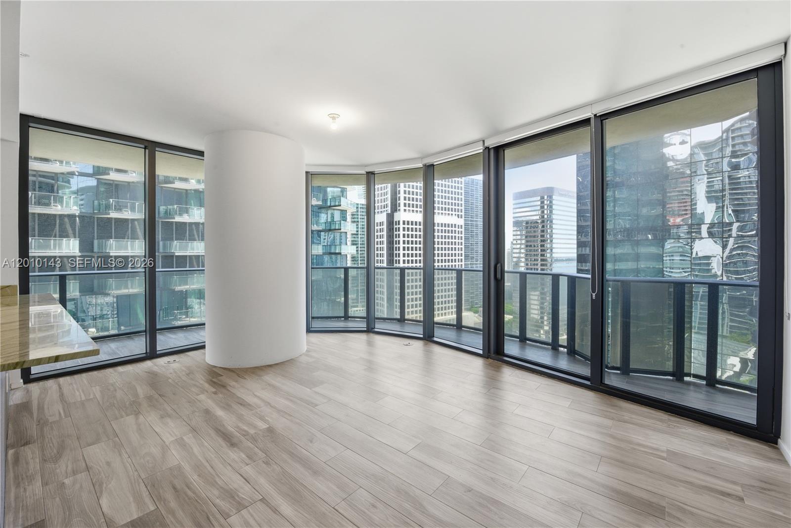An empty room features light wood-look flooring, a large structural column, and floor-to-ceiling windows — 801 S Miami Ave # 2505, Miami FL 33130, MIAMI, FL