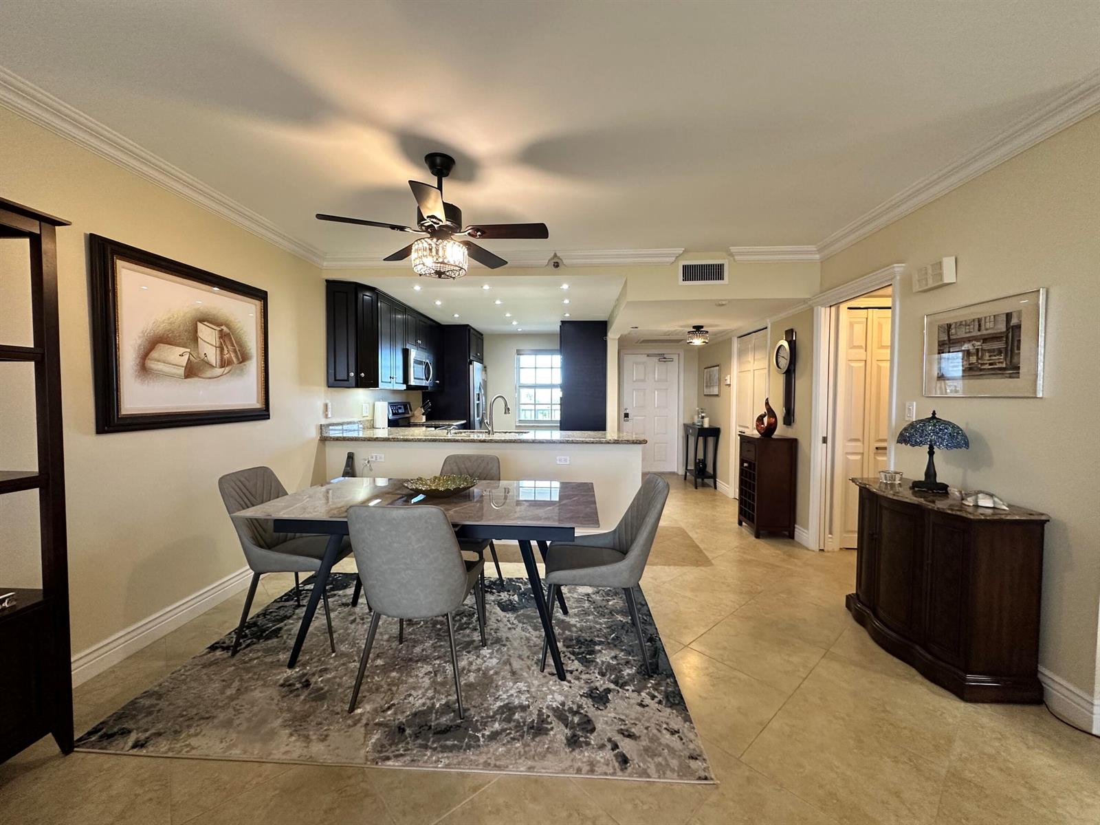 A dining area with a marble-topped table and gray chairs sits before an open kitchen — 3507 Oaks Way # 905, Pompano Beach FL 33069, POMPANO BEACH, FL