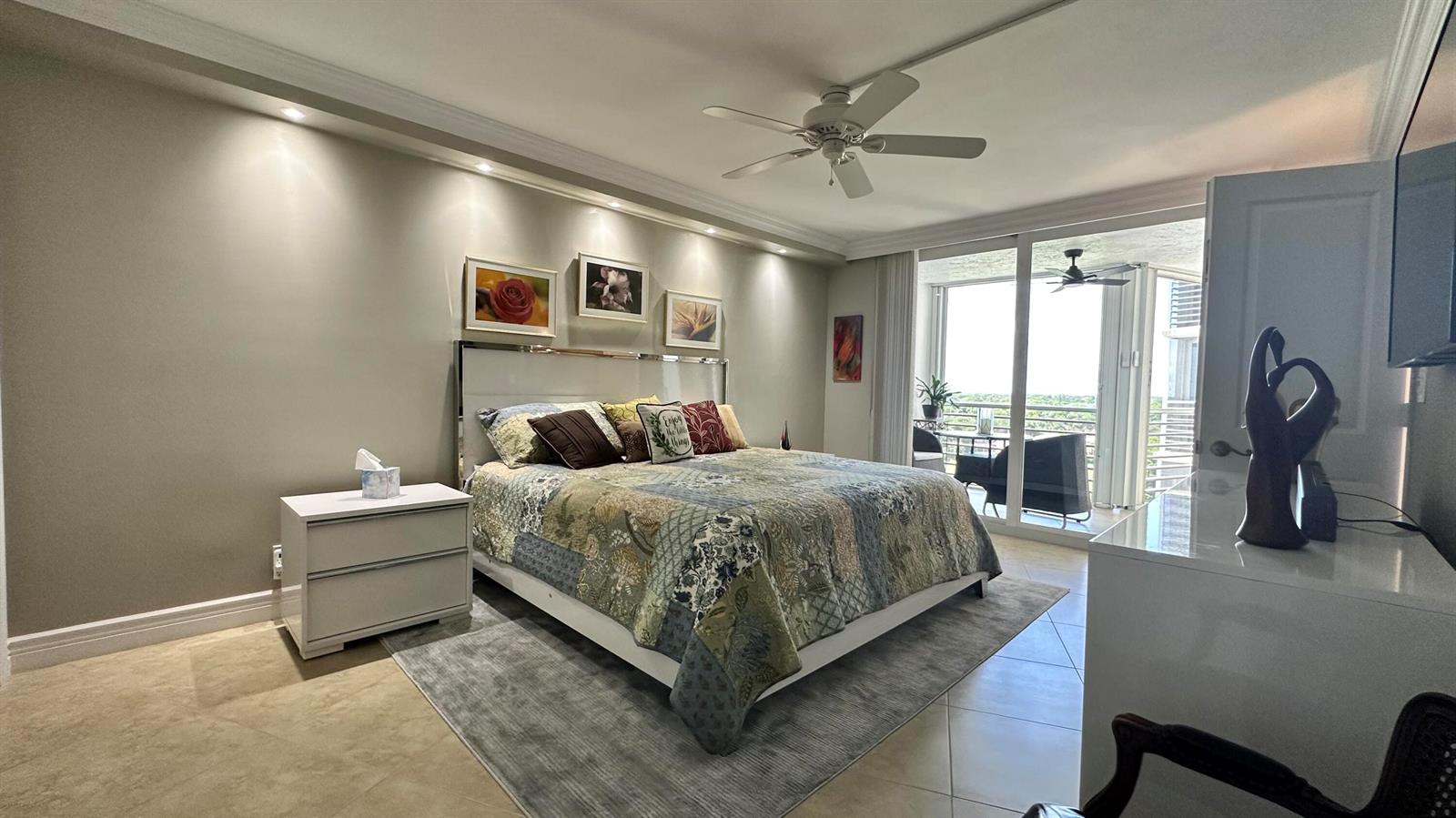 A bedroom features a patterned quilt on the bed, a ceiling fan, and a balcony — 3507 Oaks Way # 905, Pompano Beach FL 33069, POMPANO BEACH, FL