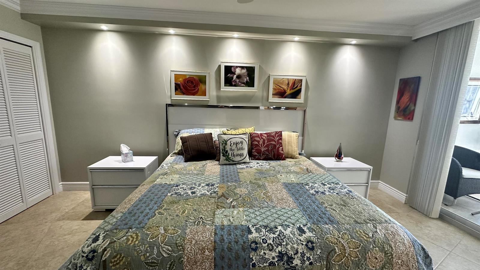A bedroom features a patchwork quilt, a white headboard, three wall pictures, and two nightstands — 3507 Oaks Way # 905, Pompano Beach FL 33069, POMPANO BEACH, FL