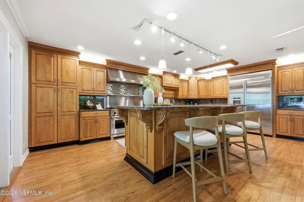 A kitchen features wood cabinets, a large island with seating, and stainless steel appliances — 7932 BREEZY POINT ROAD W, MELROSE, FL